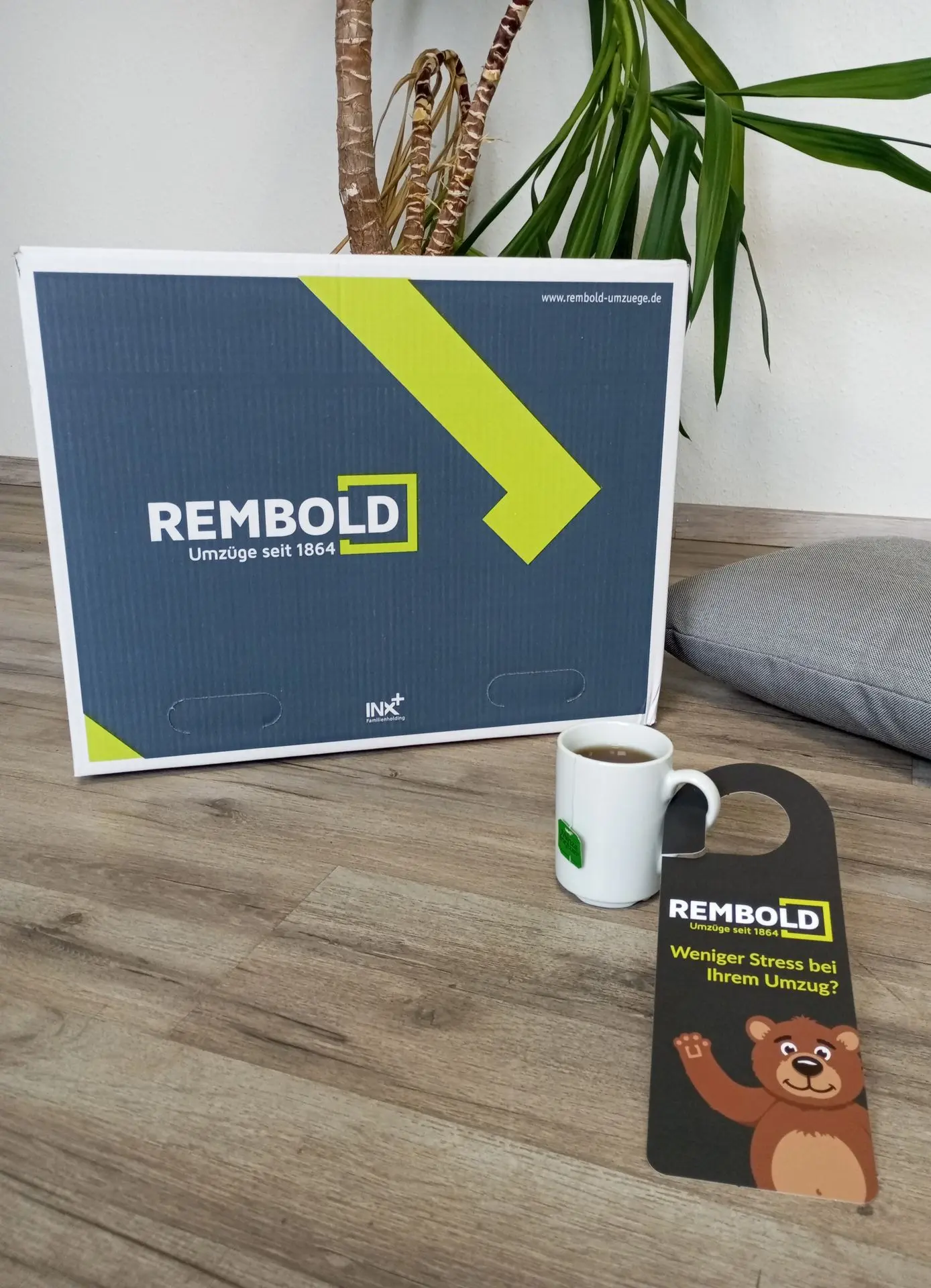 REMBOLD - Have a RELAXED move! A REMBOLD moving box and door hanger reading "REMBOLD -Less stress with your move."